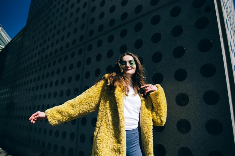 the woman stands in front of a large building wearing a yellow jacket