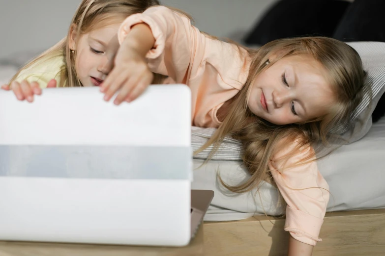 two girls laying down with an open laptop