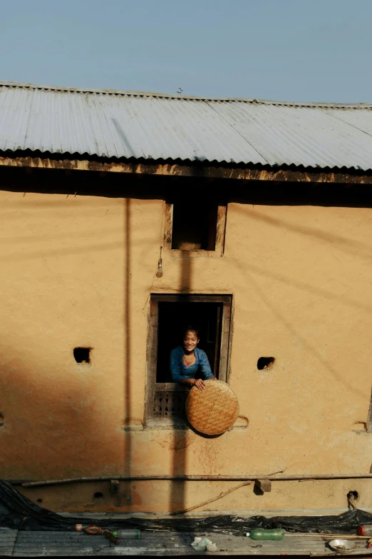 a woman sitting inside a small window next to a building