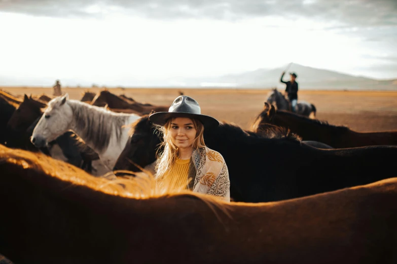 woman wearing hat and standing in front of horse pen