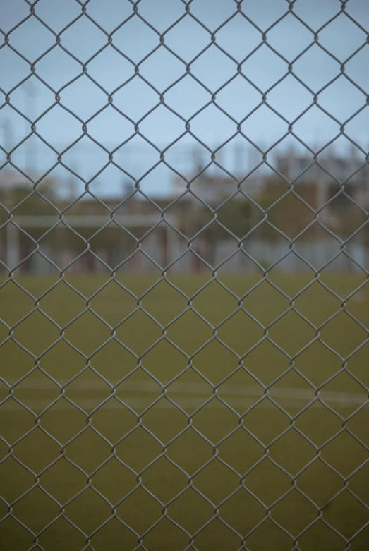 this is an image of a soccer field as viewed through a chain link fence