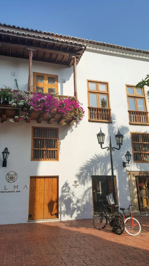 a bicycle parked in front of a white building with flowers