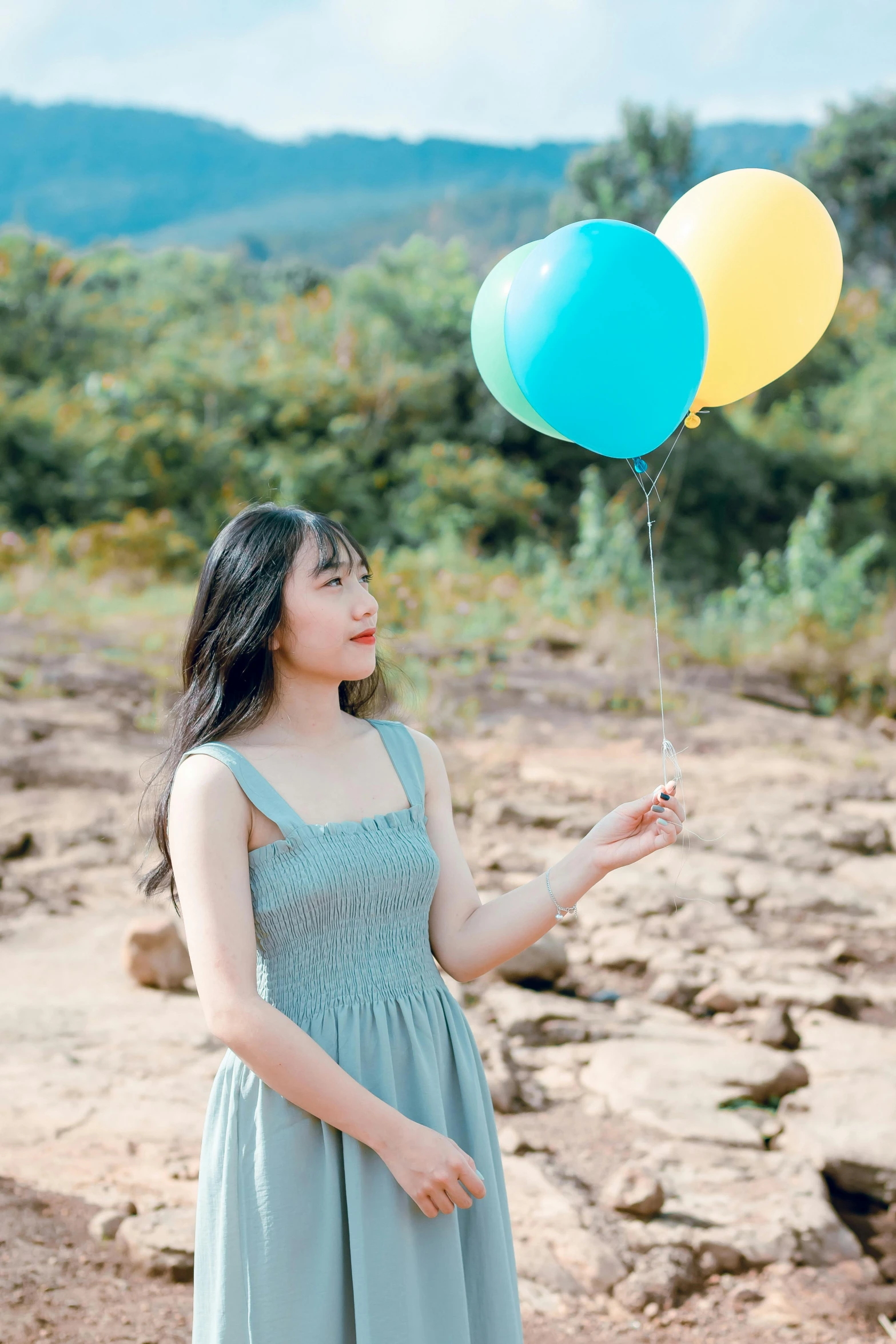 a little girl holds three balloon for her birthday