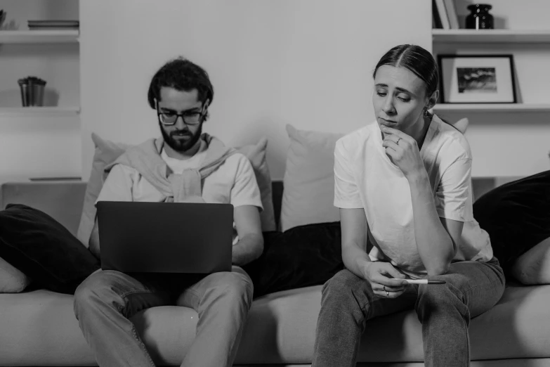 a man and woman are sitting on a couch with a laptop