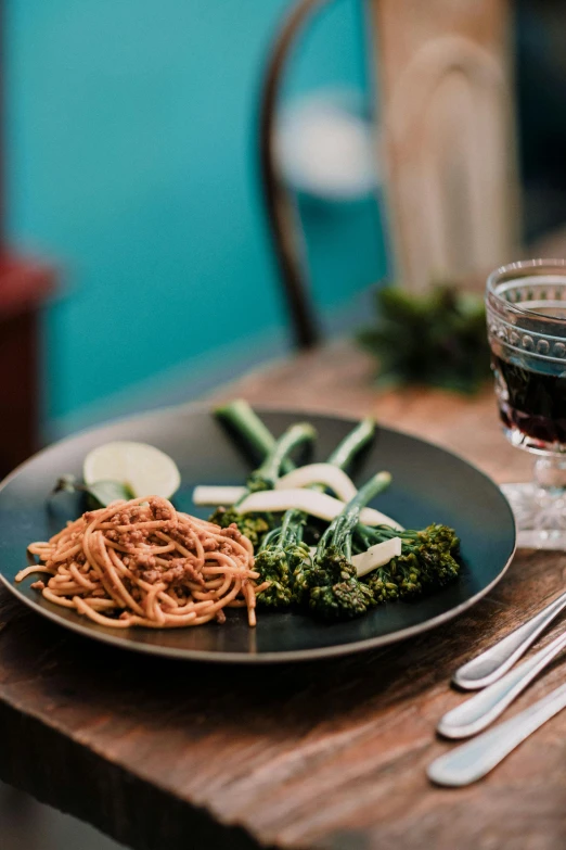 a plate with noodles and vegetables on a wooden table