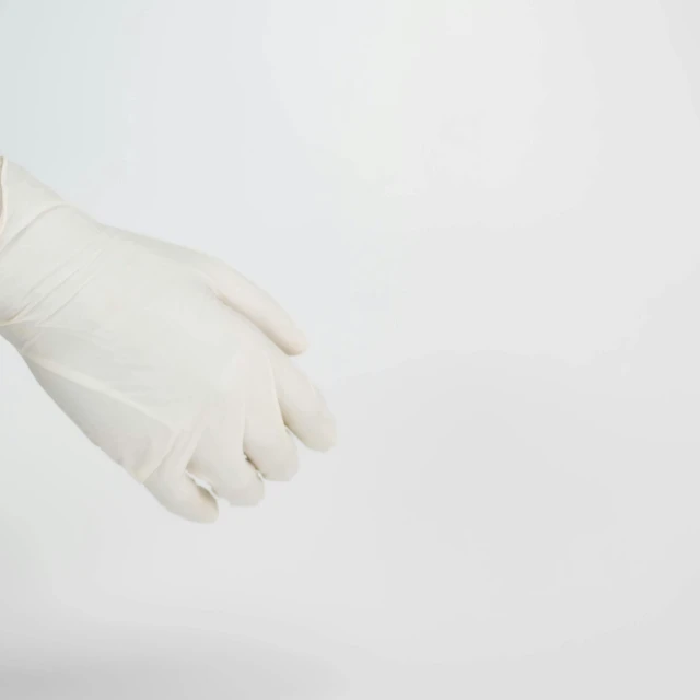 white cotton gloves on white background with hand extended back