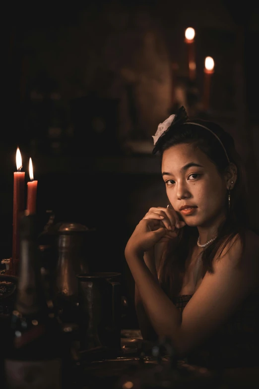 young woman in dark room, sitting next to candles