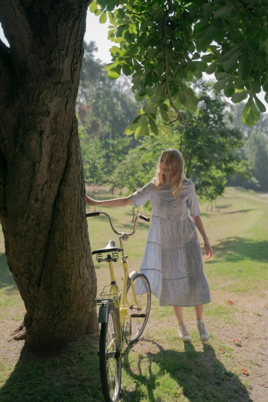 a girl in a dress standing by a bicycle