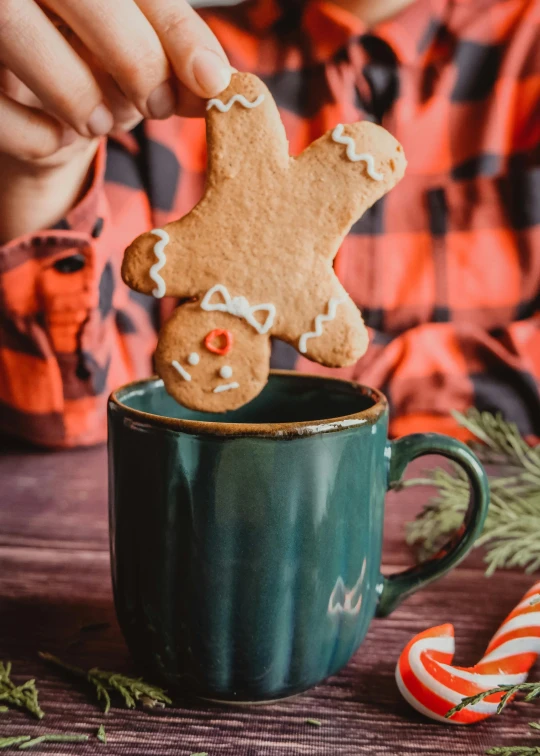 a person holding onto a cookie in a mug