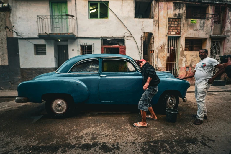 two men stand next to a classic car