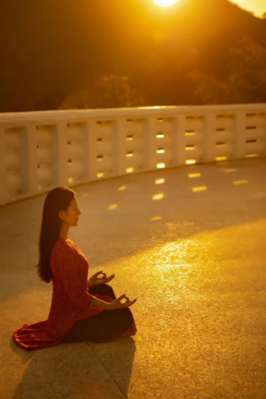 a woman sitting on the ground in front of the sun