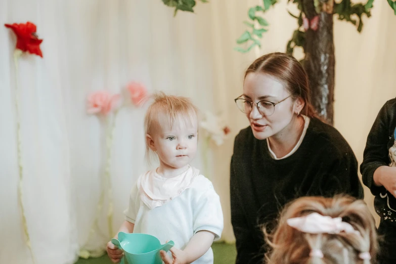 a little girl holding a green pitcher near another little girl with her hand on her hip