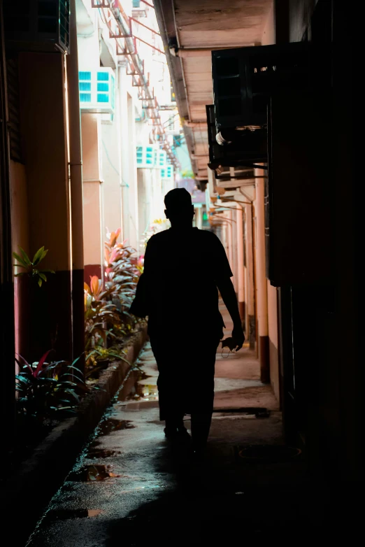 a man is walking down a walkway in the dark