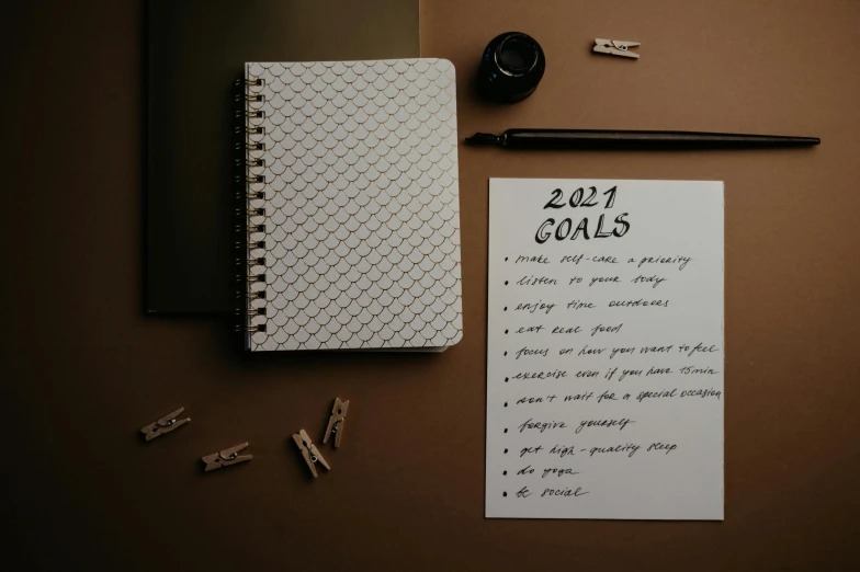 notebook and pen next to notepad on a brown surface