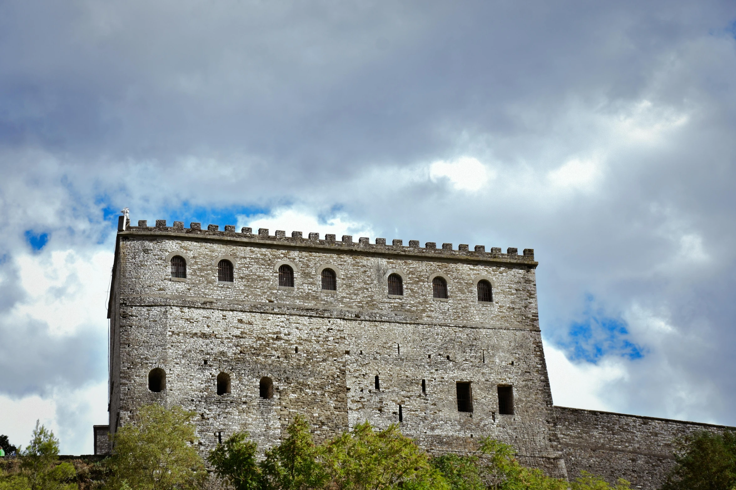 a large stone castle on top of a green hill