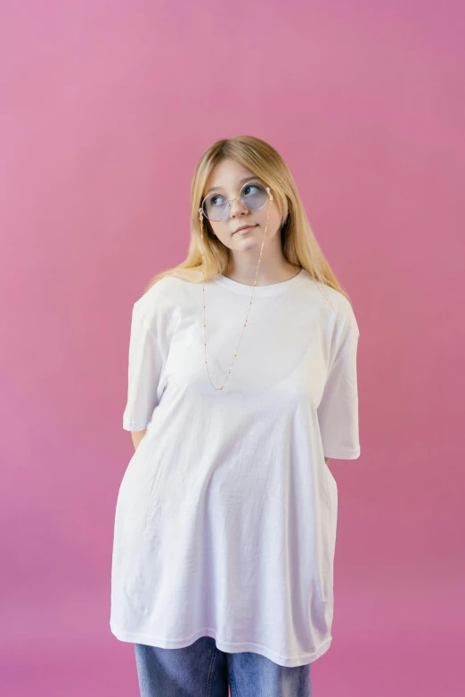 a woman wearing jeans standing in front of a pink background