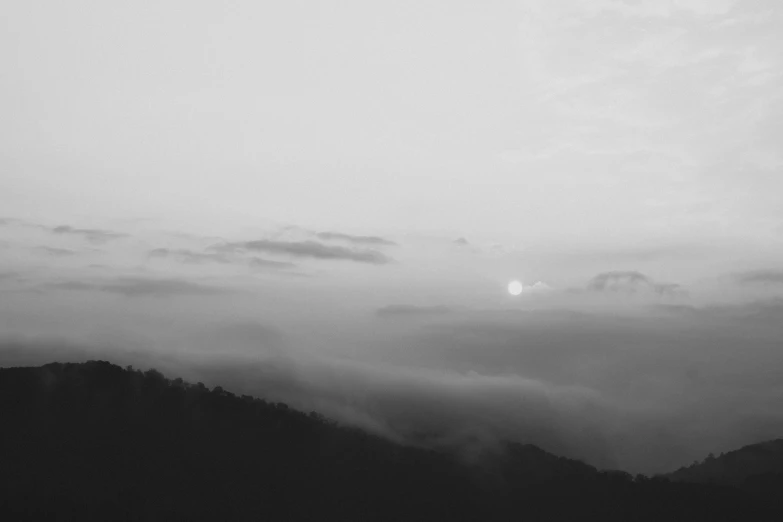 fog fills the sky as a plane flies over a mountain range