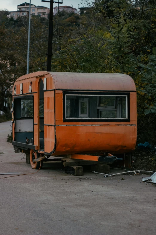 an orange trailer on the ground next to some trees