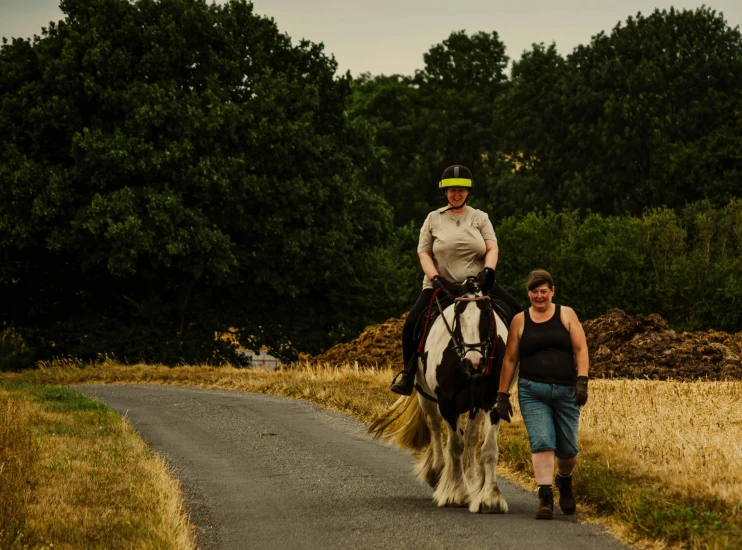 two women riding on top of horses down a road