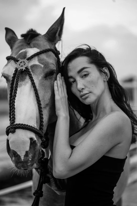 a woman holding her head near the top of a horse