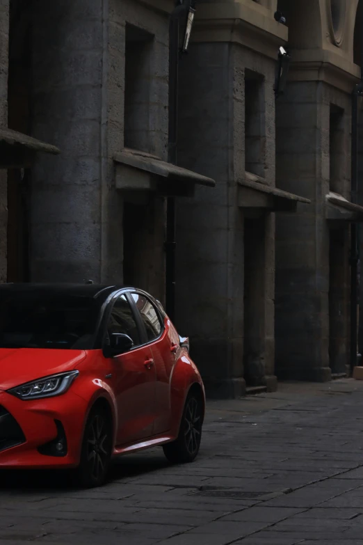 red car parked in front of large stone buildings