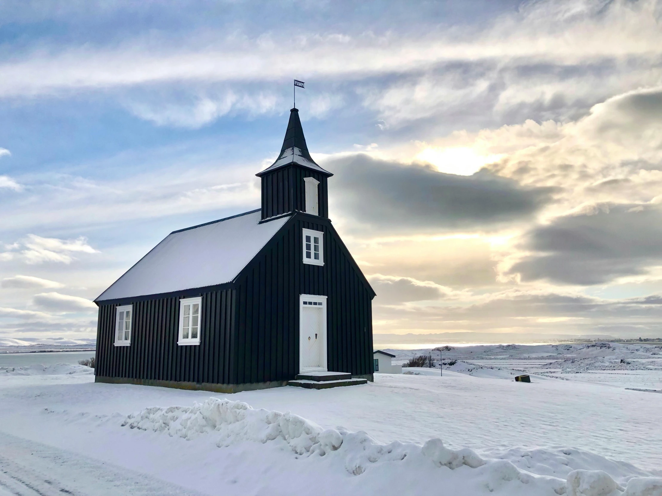 an old black church sits on the snow covered road