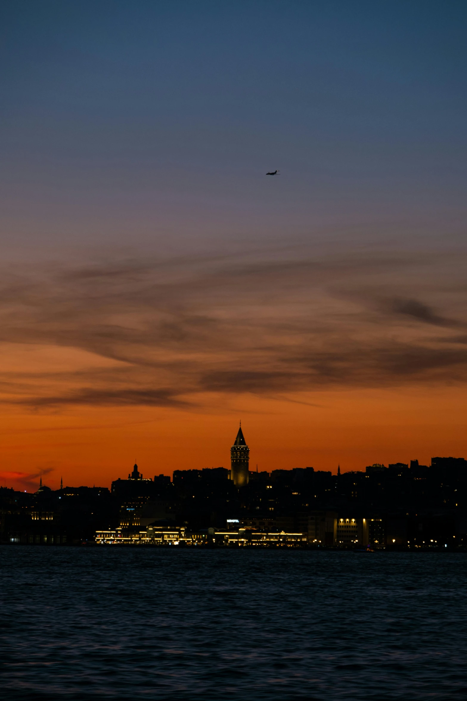 an airplane flying over the water with the skyline in the background