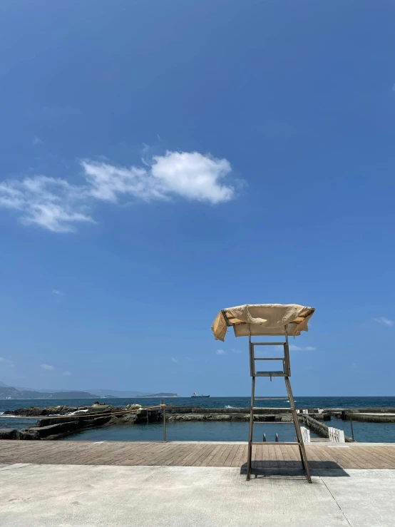 a ladder stands next to an umbrella with a lake in the background