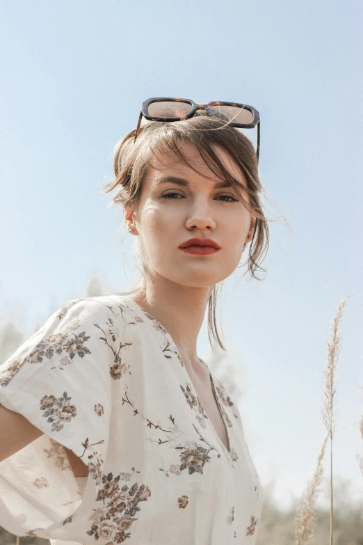 woman wearing glasses in a flowery dress by a sunny sky