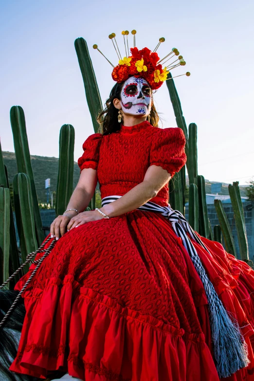 a woman in a red dress sitting next to a large cactus