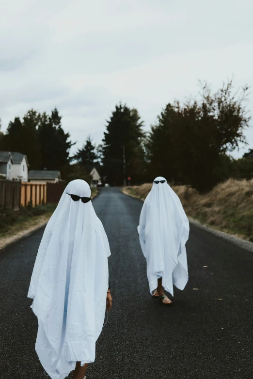 two men wearing ghost like clothing walking down a road