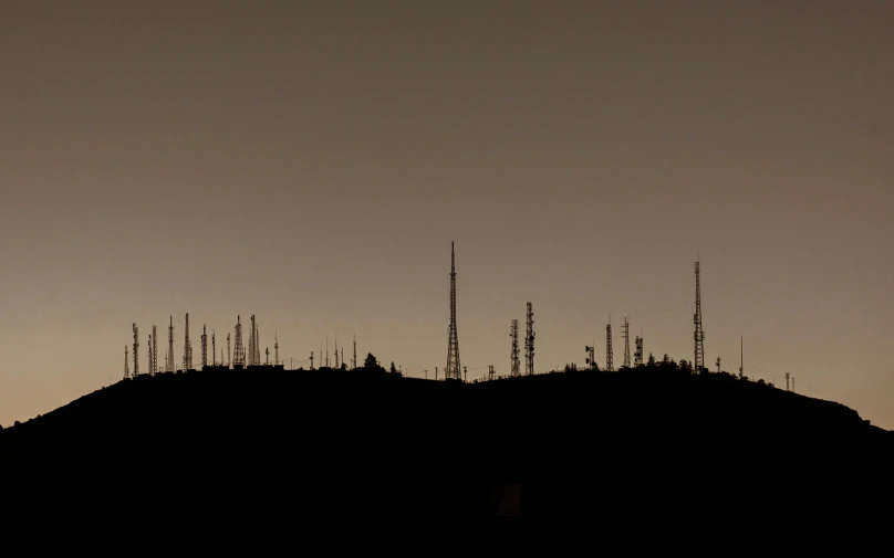 a hill covered in trees and lots of tall antennas