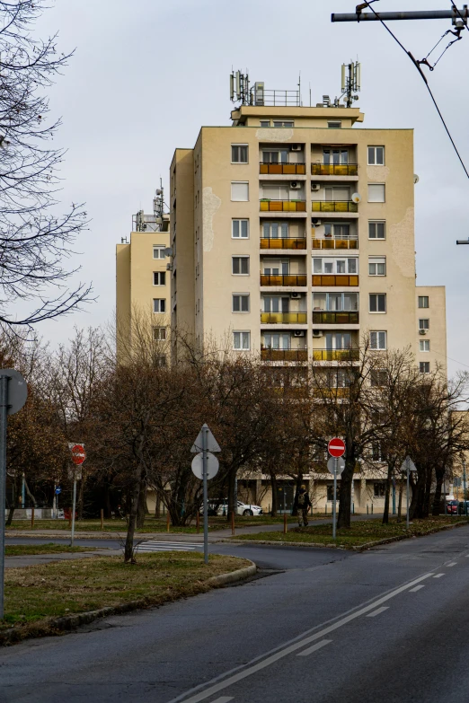 an apartment building sits at the top of a hill next to an empty street