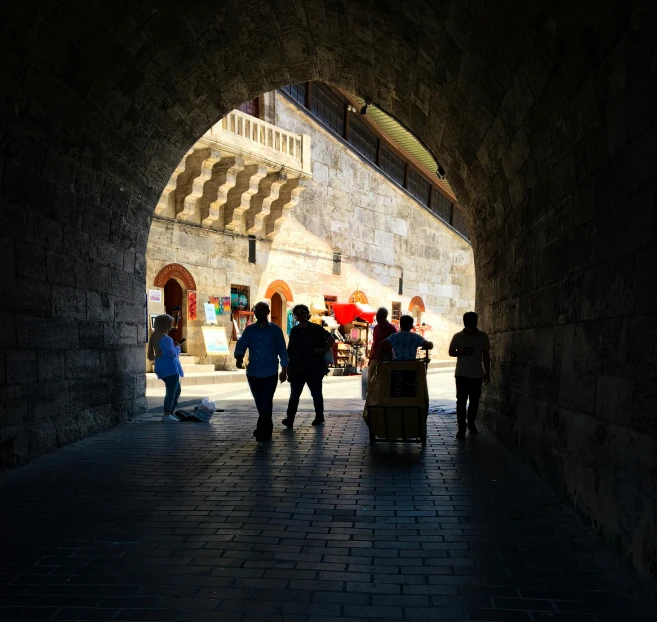 a large tunnel on a cobblestone road with pedestrians