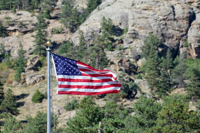 a large american flag is waving at the top of a mountain