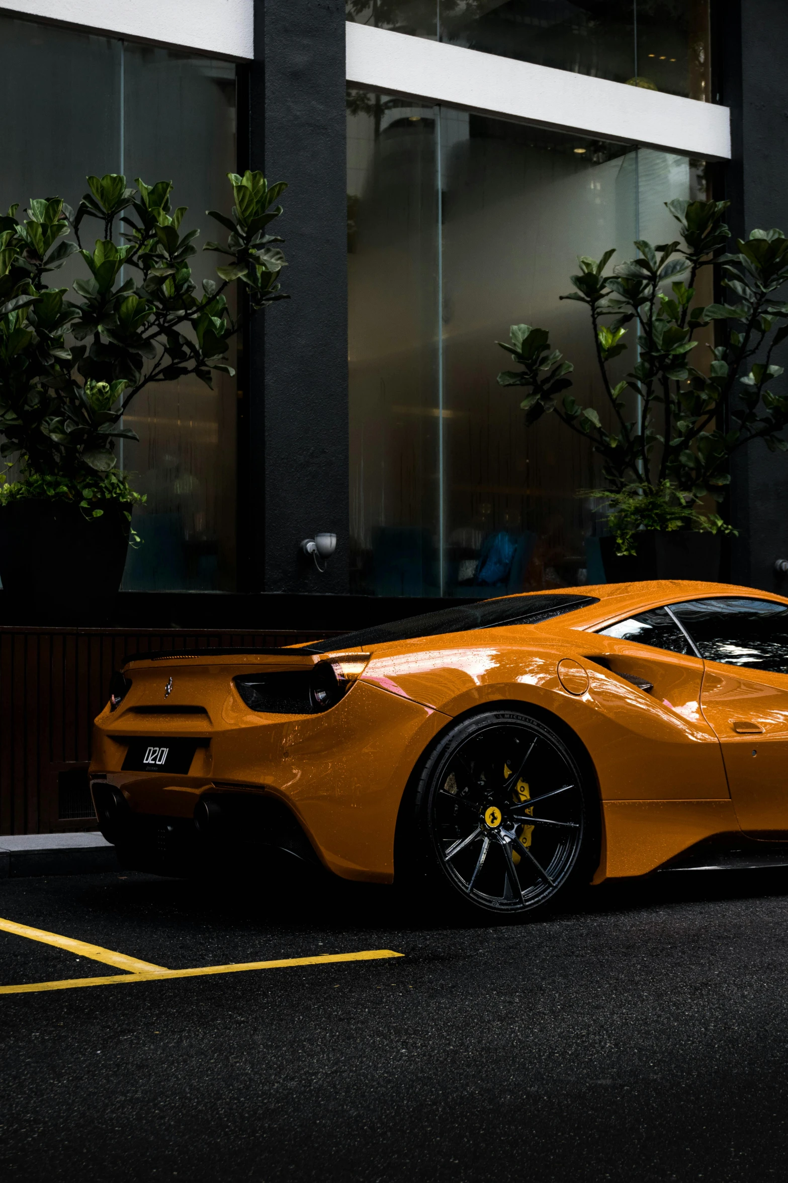 a gold ferrari on a city street next to potted plant