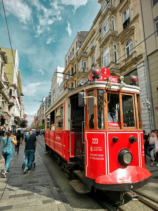 people walking along a street near an old fashioned tram