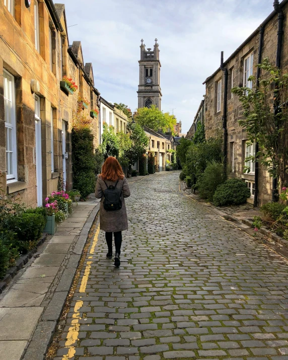 a woman walking down the middle of a cobblestone road