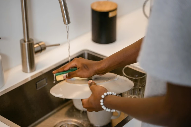 a woman is doing soing on the bowl in her kitchen