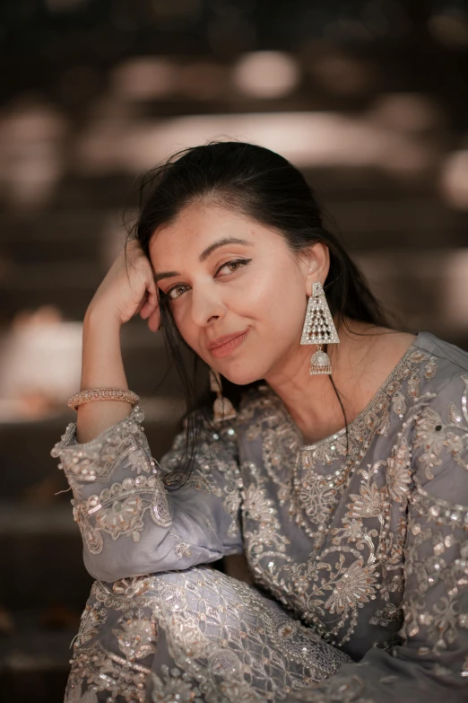 a woman in an ethnic sari sits down wearing silver earrings