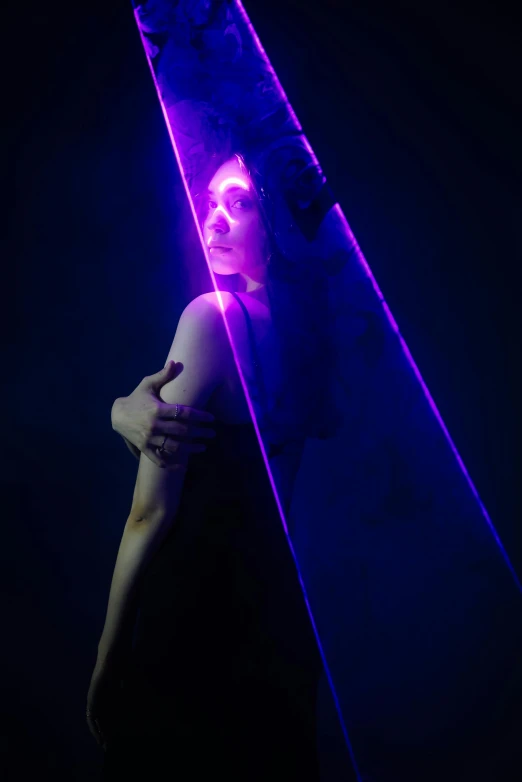 woman in dark with neon dress leaning against pole