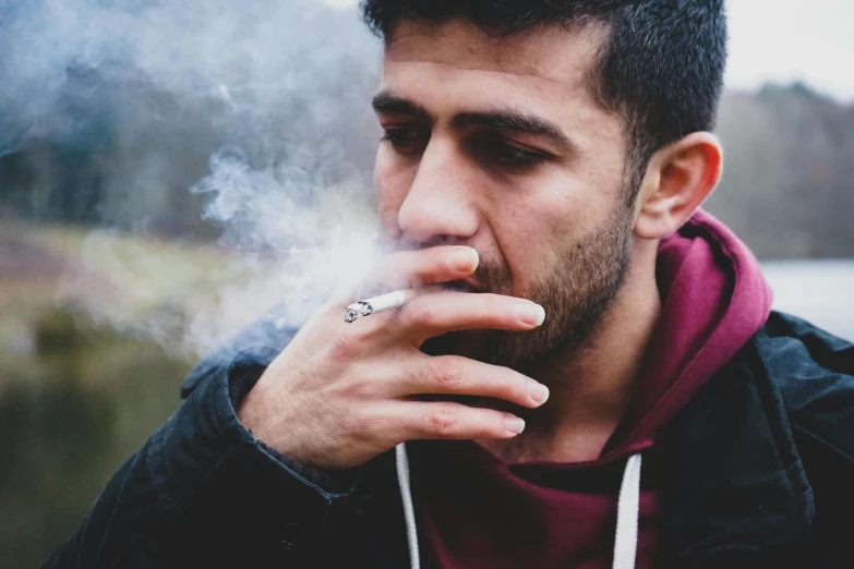 a man wearing a jacket smoking a cigarette