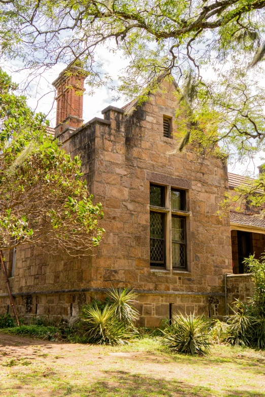 an old brick building sitting under a tree with windows