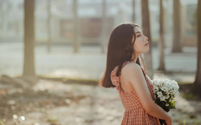 a woman in a dress looks up at the trees