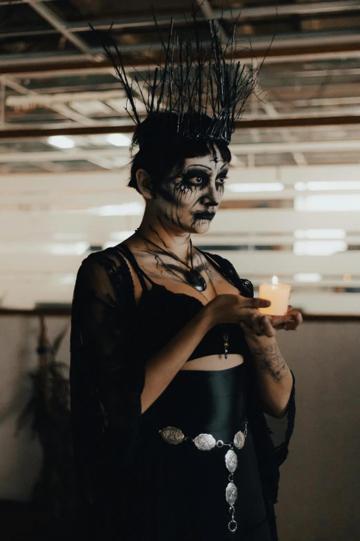 a woman wearing makeup is holding a candle