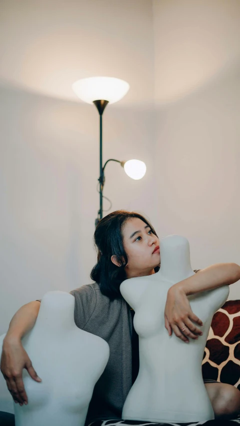 a woman sitting next to a large white vase