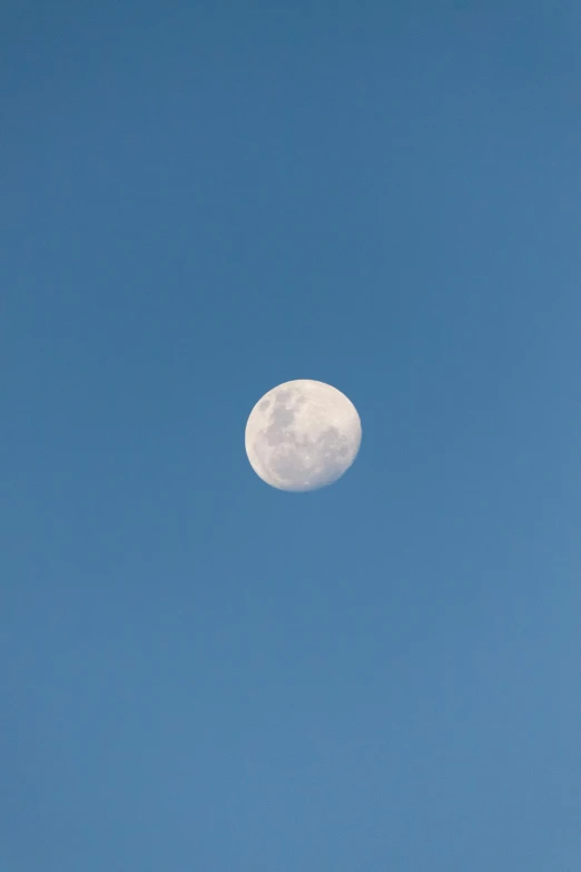 the moon is almost obscured by a very bright blue sky