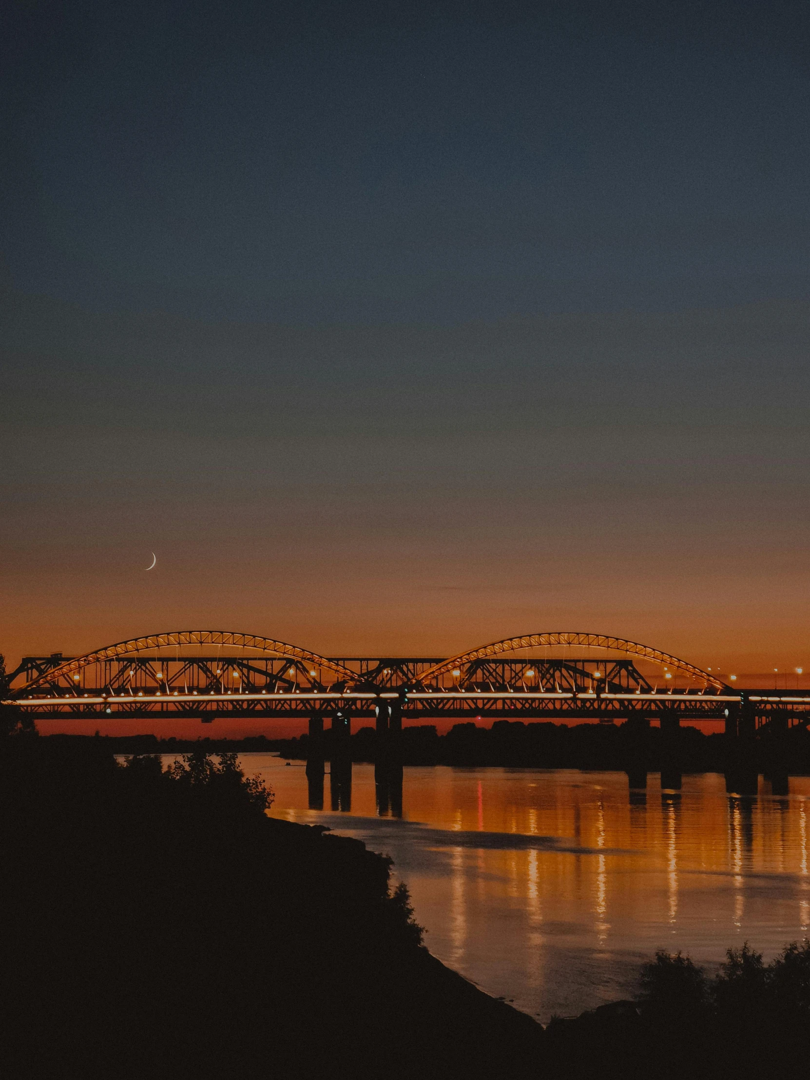 a bridge in the distance with the sky reflected on it