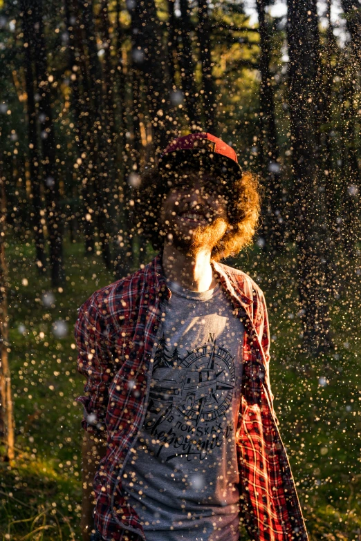 person in woods covered in falling raindrops with head on hips