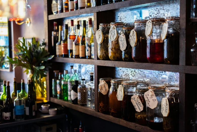 several jars of various kinds of drinks on shelves